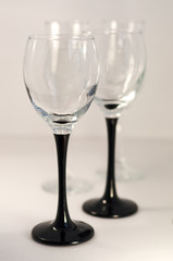 Two glasses for wine on black pedestals on a light background