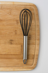 A Whisk on Wooden Cutting Board on White Background