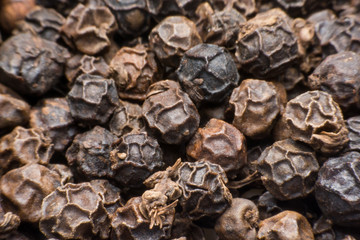 Black pepper grains as background close up