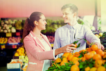 Young brunette girl and boyfriend buying citruses i