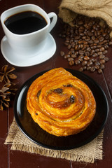 Bread on black plate and black coffee with coffee beans in cloth bag on wooden table