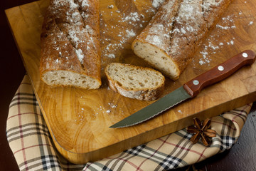 French bread Sliced ​​on a wooden cutting board with a knife on a wooden table.