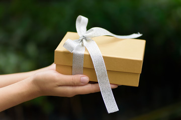 Golden gift box in hand for giving in holidays