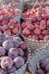 plums and apples in baskets at the market