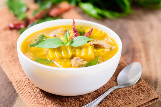 Thai food.Spicy pumpkin soup with pork in a bowl on brown fabric and wooden background