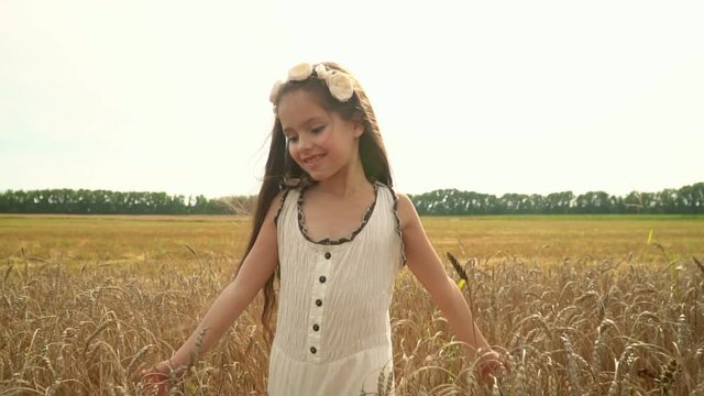 The girl with long dark hair. The girl runs hands over wheat ears. The lovely girl walks on the Russian field. The girl smiles for the camera. Slow motion