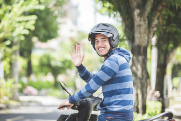 man riding a motorbike and waving hand