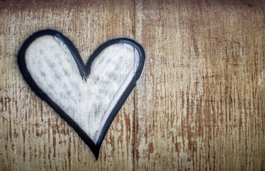 A white spray painted heart outlined in black painted onto a rusted metal backdrop