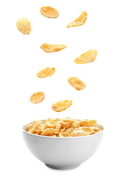 Corn flakes falling into bowl on white background