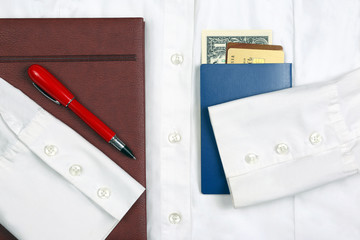passport, money, pen, notebook and Bank cards are on a white shirt with sleeves