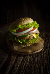 Pork hamburger Homemade with grilled bacon contains vegetables, cheese, lettuce, onion, chilli, spices in a wooden dish on a wooden floor.