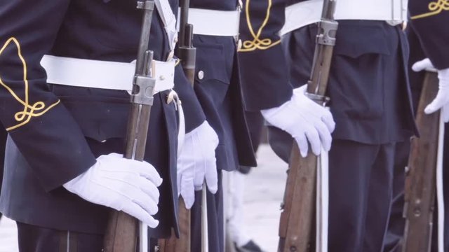 Cadets wearing white gloves during a military parade.
