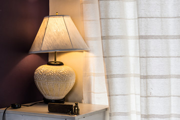 Vintage lamp beside the window curtain in the warm bedroom.