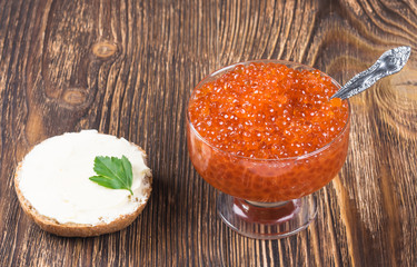 plate of red caviar with a piece of bread, on a wooden table