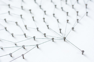 nails in white paper simulation network. linked together by black cotton