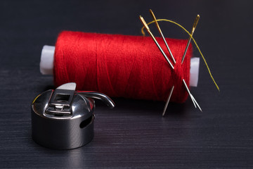 red skein of thread at the needle and the Shuttle hook for sewing machine, on a dark background