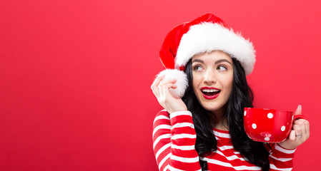 Happy young woman with Santa hat drinking coffee