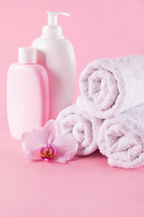 Obraz na płótnie Canvas Towels with shower gel and body lotion on pink background.