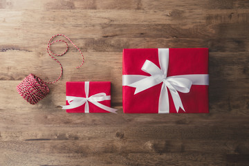 Red Christmas and New Year holiday gift boxes with white ribbon bows and decorating rope on wood table