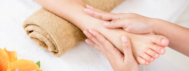Therapist giving relaxing reflexology Thai foot massage treatment to a woman in spa