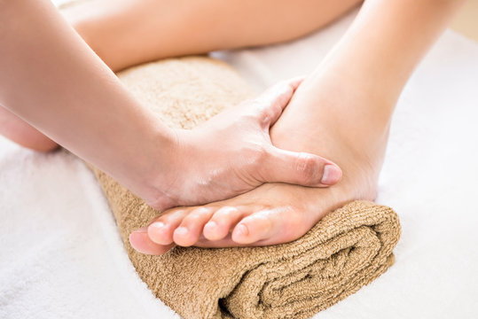 Therapist giving relaxing reflexology foot massage treatment to a woman in spa