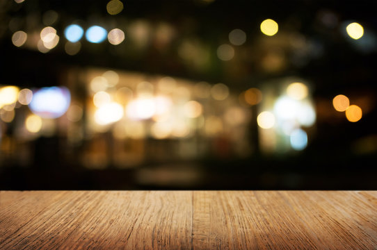 empty wood table in front of blurred montage night market bokeh background