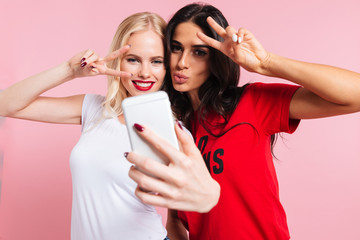 Picture of Two pretty smiling women making selfie on smartphone