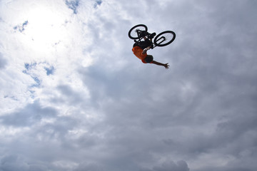 Silhouette of a young man freestyle stunt cyclist flying in the sky