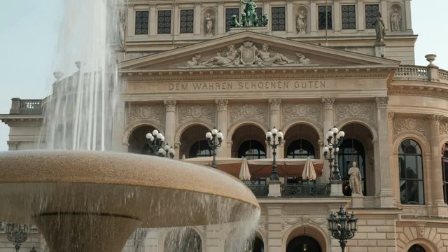 Static close shot of the upper floors of Alte Oper, the opera theatre in Frankfurt taken from Opernplatz framed by a fountain