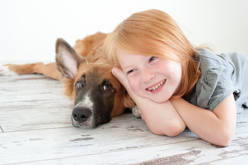 Red-haired puppy and red-haired girl lie on the floor