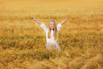 Happy girl in wheat field in summer evening