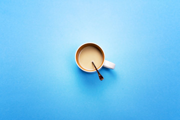 A Cup with coffee and spoon on a colored background. The concept of coffee breaks