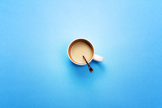 A Cup with coffee and spoon on a colored background. The concept of coffee breaks