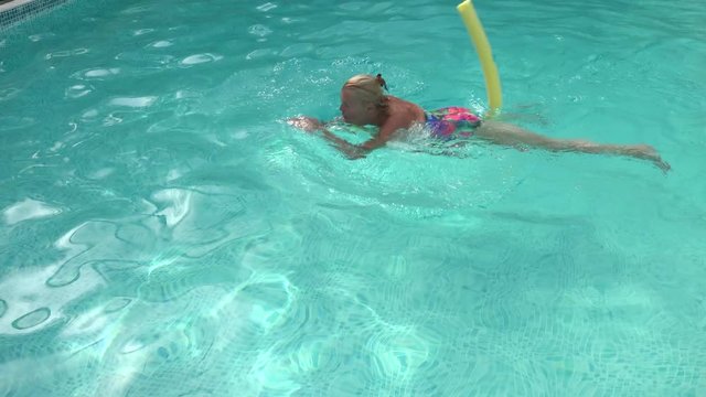 Older Caucasian women relaxing with foam noodles in swimming pool