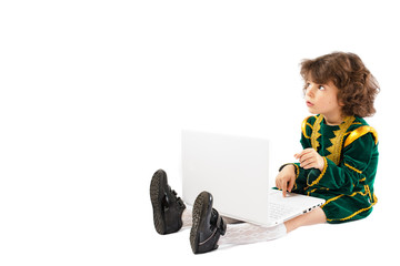 Baby boy In a prince's costume sitting on the floor and typing on laptop.Child blogging in internet.
