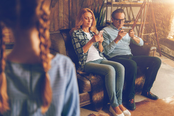 Obraz premium Married couple with phones ignoring their child