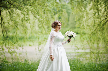 Portrait of a beautiful young bride posing with a bouquet outdoor on her own.
