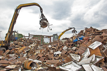 Sorting and loading of scrap metal./Excavator is loading scrap metal junk into a bin at a garbage dump or recycling center.