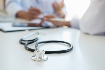 Patient listening intently to a male doctor explaining patient symptoms or asking a question as they discuss paperwork together in a consultation