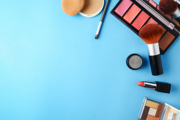 Top view of cosmetics set for makeup on a blue background. Free space for text.