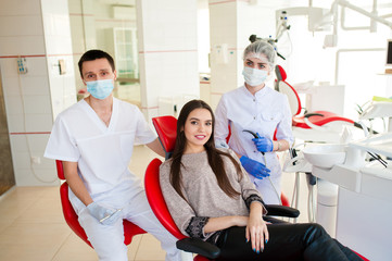 Fototapeta premium A dentist with an assistant, heals teeth to a beautiful girl.