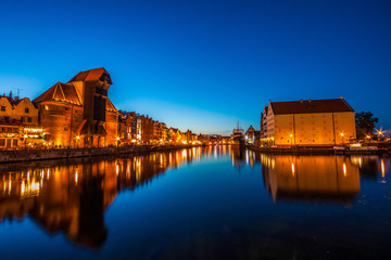 Fototapeta premium Gdansk old town and famous crane, Polish Zuraw. View from Motlawa river, Poland at romantic sunset, night.