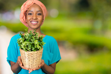 African woman holding plant in vase