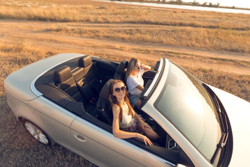 Two attractive young women in a cabriolet car