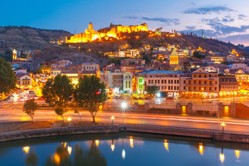Amazing view of Olt town with Narikala ancient fortress, St Nicholas Church and Kura river in night Illumination during evening blue hour, Tbilisi, Georgia.