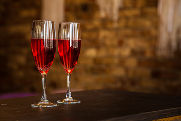 Two glass glasses, a decanter with pink champagne, wine, stand on a blurred background of a brick wall. Romantic evening, date. Place for the inscription. Titles