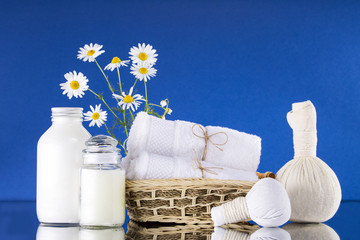 Spa. A bouquet of chamomile. White bottle with cream. The background is blue.