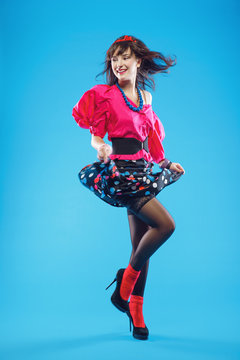 Young woman in colorful old-fashion clothes in pinup style dancing