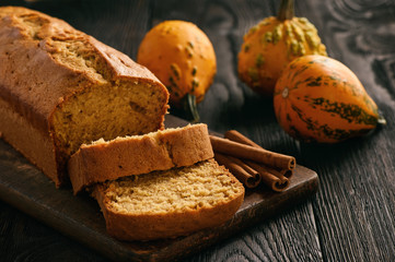 Homemade pumpkin cake on black wooden background.