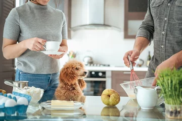 Crédence de cuisine en verre imprimé Cuisinier Un couple avec un chien prépare le petit-déjeuner. Couple sur la cuisine cuisiner ensemble.